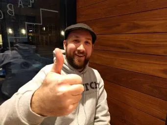 Smiling improviser in a CATCh hoodie giving a thumbs up