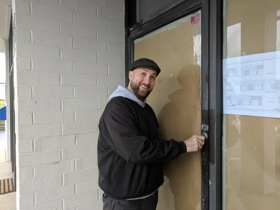 Man at the glass front door of a new storefront