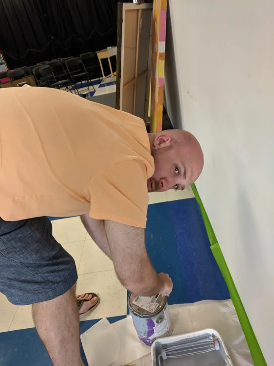 Volunteer painting along taped edges near the floor