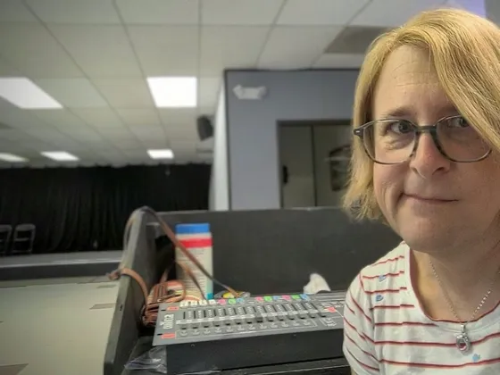Volunteer smiling beside the sound board