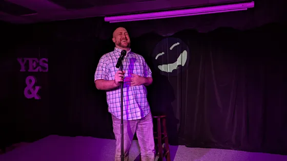 Performer with a microphone on a purple-lit stage